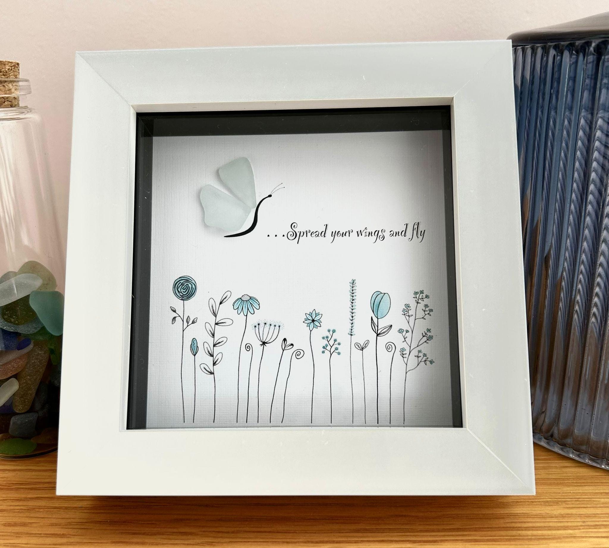May include: White framed artwork with a butterfly design and the text "...Spread your wings and fly." The artwork features a sea glass butterfly and a floral design in blue and black.
